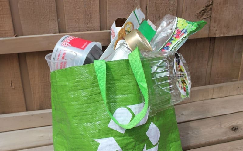 Sac vert rempli d'emballages de plastique à usage unique